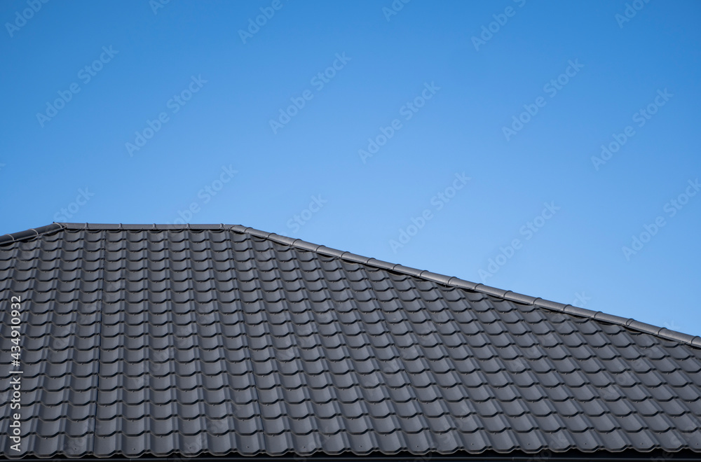 Brown corrugated metal profile roof installed on a modern house. The roof of corrugated sheet. Roofing of metal profile wavy shape. Modern roof made of metal. Metal roofing. Brown corrugated metal profile roof installed on a modern house. The roof of corrugated sheet. Roofing of metal profile wavy shape. Modern roof made of metal. Metal roofing.