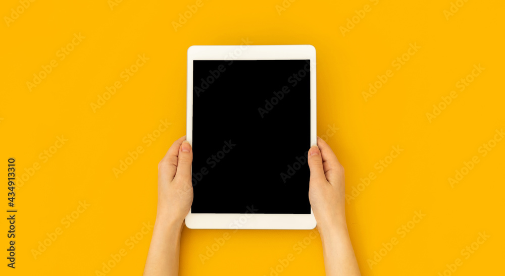 Woman hand holds digital tablet mockup with blank screen, education and application concept template, bright yellow background, top view and copy space photo Woman hand holds digital tablet mockup with blank screen, education and application concept template, bright yellow background, top view and copy space photo