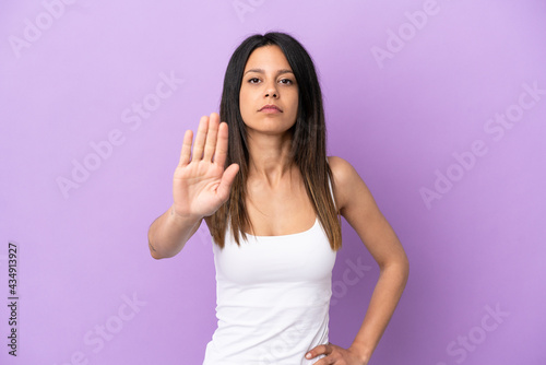 Young caucasian woman isolated on purple background making stop gesture
