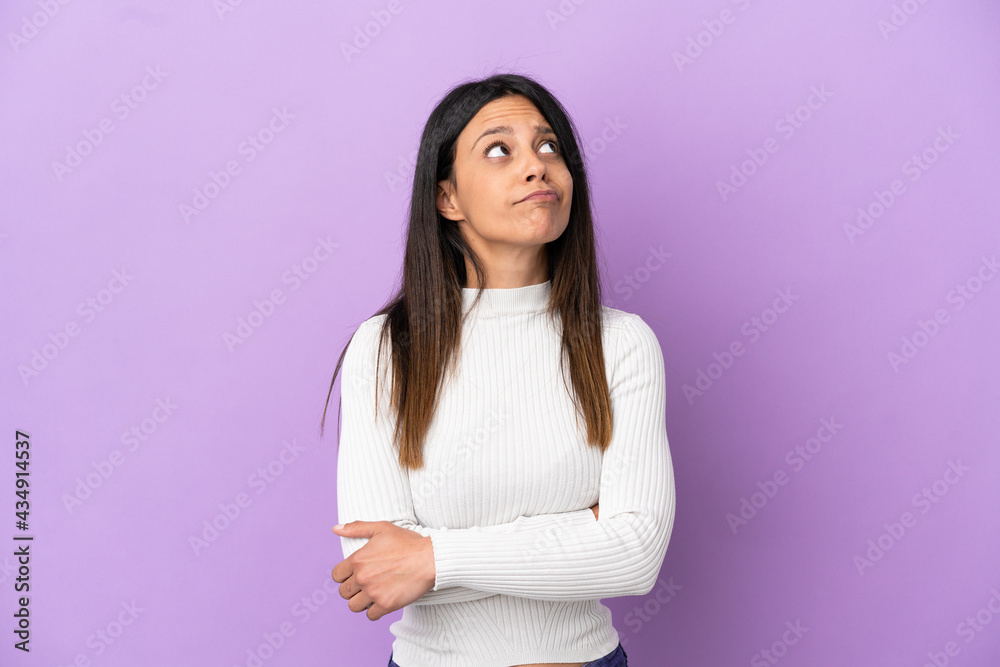 Young caucasian woman isolated on purple background and looking up Young caucasian woman isolated on purple background and looking up