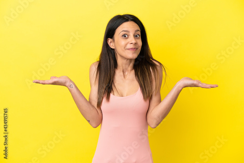 Young caucasian woman isolated on yellow background having doubts while raising hands