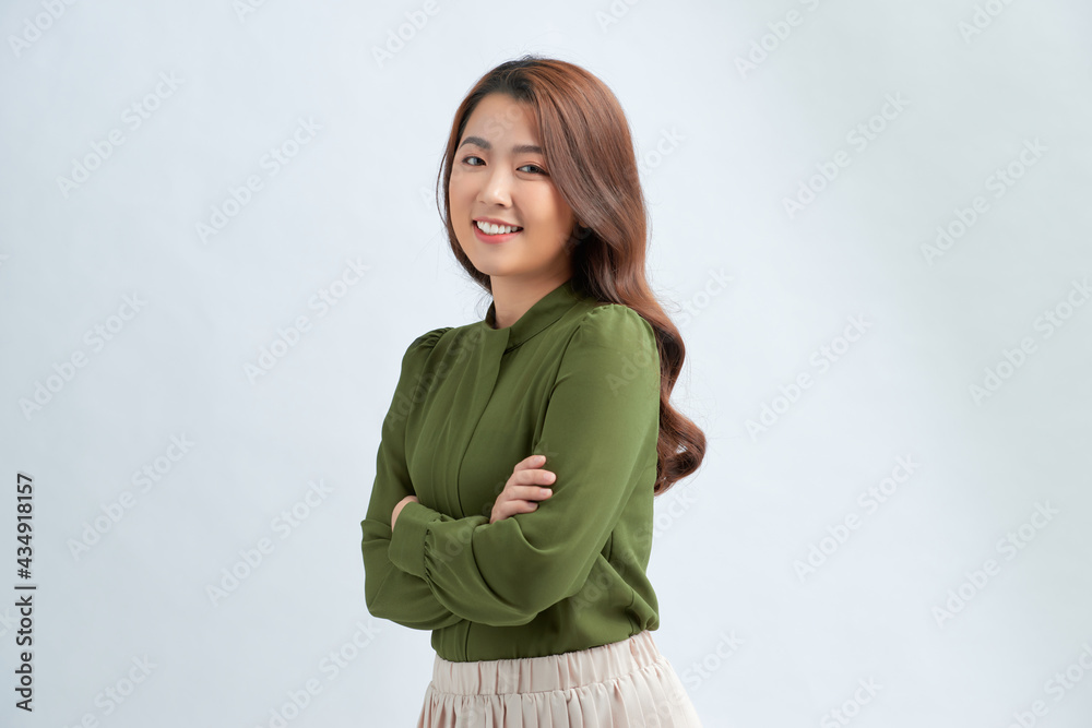 Portrait of a happy woman standing with arms folded isolated on a white background