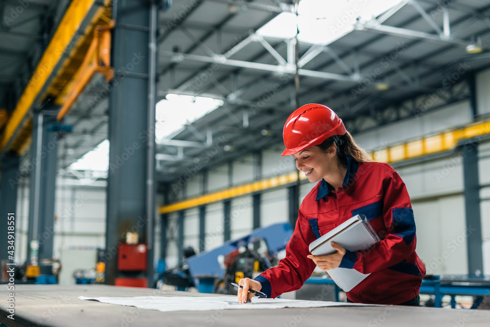 Female worker working with blueprints in heavy industry factory. Female worker working with blueprints in heavy industry factory.