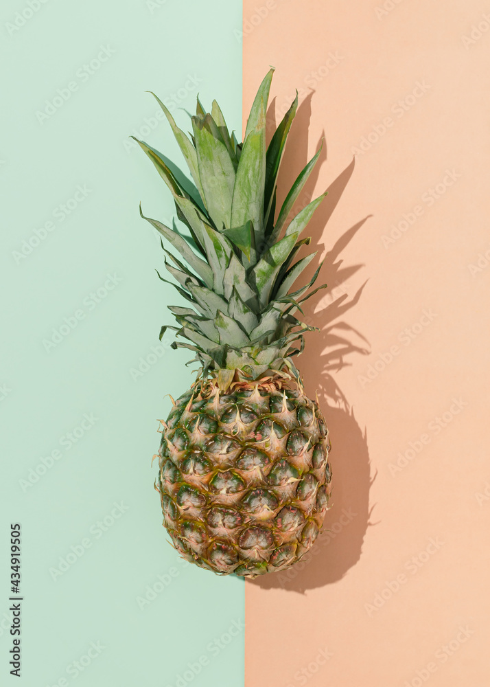 Fresh pineapple fruit with sunny day shadow on mint green and bright terracotta background. Minimal exotic food concept.