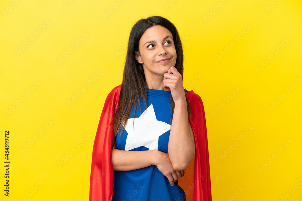 Woman isolated on yellow background in superhero costume and thinking Woman isolated on yellow background in superhero costume and thinking