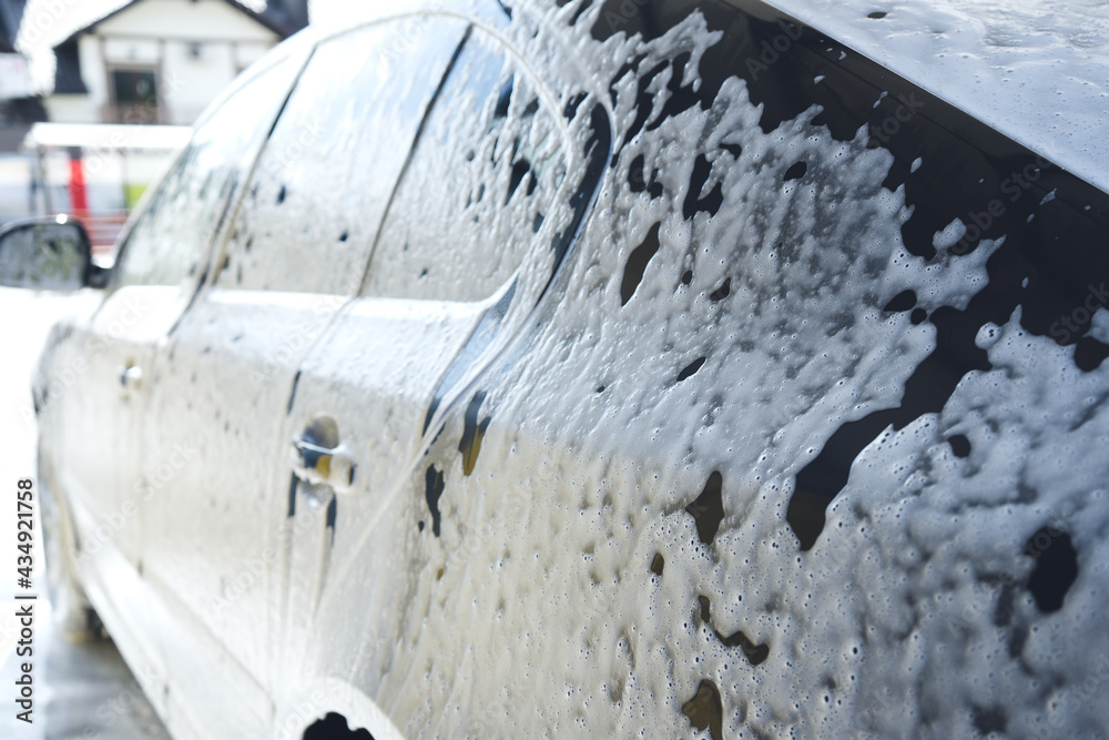Car in white foam on a manual car wash. Gray car washed in white foam. Auto at the car wash