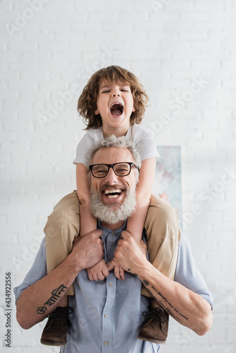 Excited kid hugging smiling grandfather photo