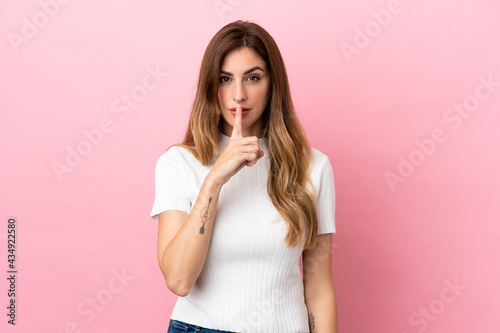 Caucasian woman isolated on pink background showing a sign of silence gesture putting finger in mouth