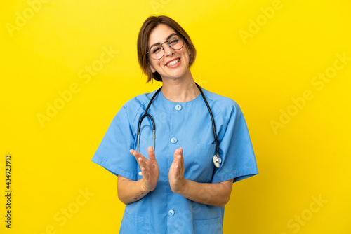 Surgeon doctor woman isolated on yellow background applauding after presentation in a conference