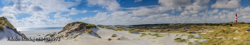 Breathtaking beautiful panorama of coastal landscape at Nort sea and lighthouse on the Isle Amrum, Schleswig-Holstein, Germany.  Stunning view from Wadden Sea coastline with sandy beach and wide dunes