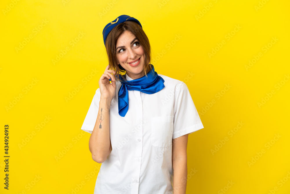Airplane stewardess woman isolated on yellow background thinking an idea Airplane stewardess woman isolated on yellow background thinking an idea