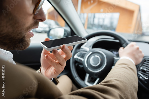 partial view of bearded man recording voice message smartphone while driving car