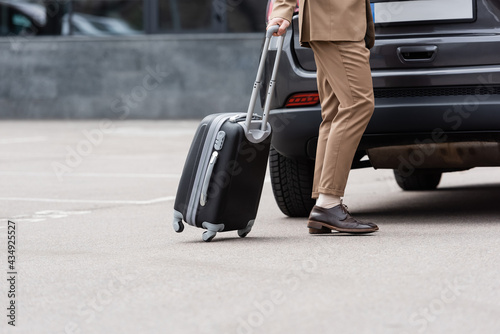 cropped view of man in suit walking near car with suitcase © LIGHTFIELD STUDIOS