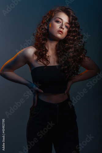 Beauty young woman with curly big and long hair. Glamour lady on dark blue background. Cute woman face wavy hair, perfect make up, red lips