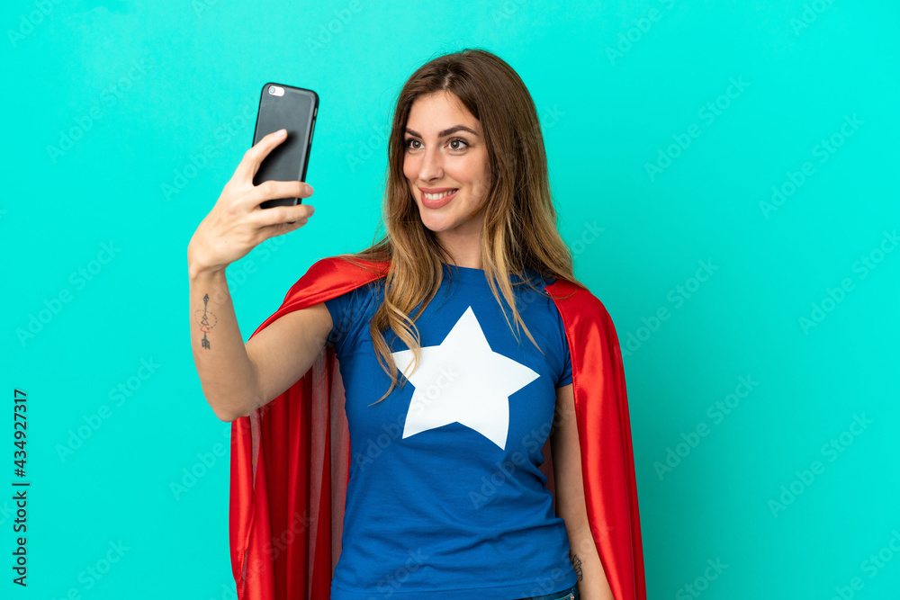 Naklejka premium Super Hero caucasian woman isolated on blue background making a selfie