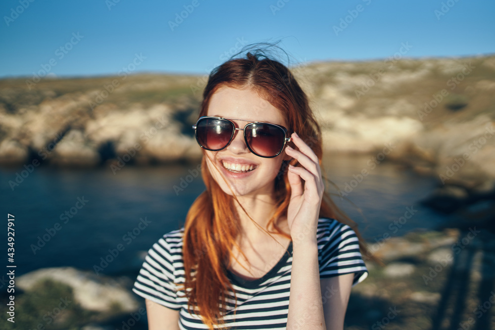 portrait of a happy traveler in a t-shirt and glasses and near the sea in the mountains