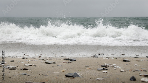 Ujęcie na wprost kamienistej plaży i spienionej fali