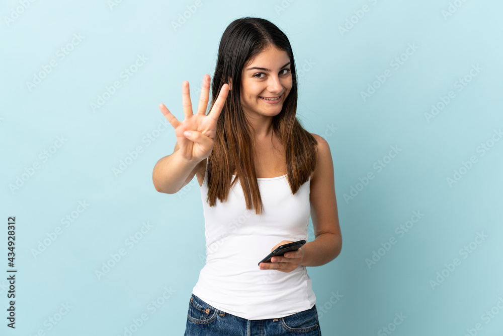 Young caucasian woman using mobile phone isolated on blue background happy and counting four with fingers Young caucasian woman using mobile phone isolated on blue background happy and counting four with fingers