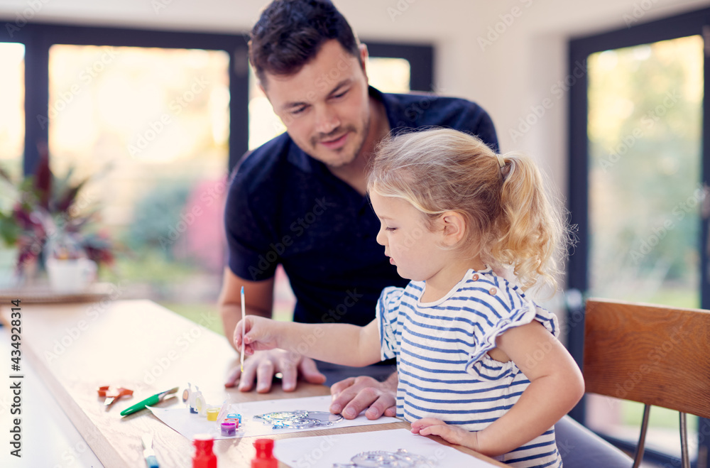 Father And Young Daughter Having Fun Doing Craft On Table At Home Together