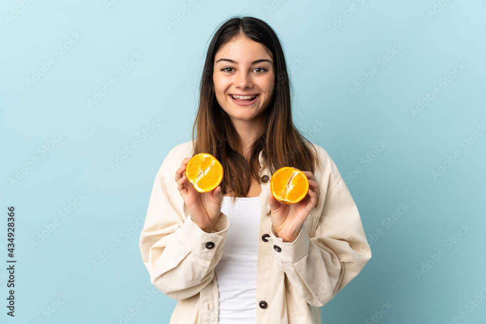 Young caucasian woman isolated on blue background holding an orange Young caucasian woman isolated on blue background holding an orange