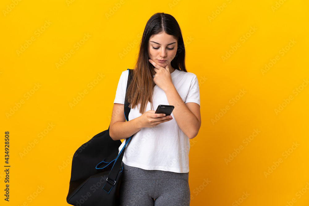 Young sport woman with sport bag isolated on yellow background thinking and sending a message Young sport woman with sport bag isolated on yellow background thinking and sending a message
