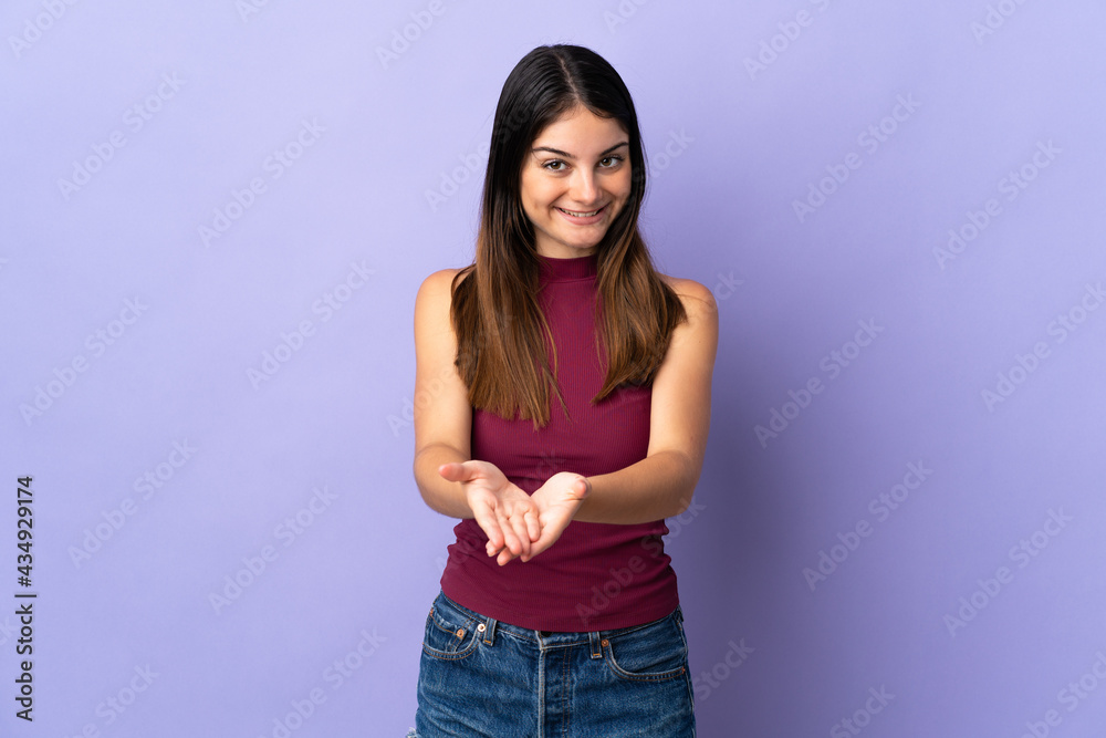 Young caucasian woman isolated on purple background holding copyspace imaginary on the palm to insert an ad