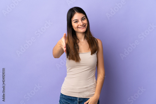 Young caucasian woman isolated on purple background shaking hands for closing a good deal