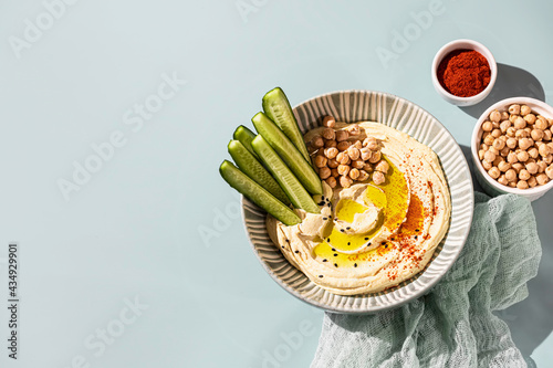 Chickpea hummus with olive oil and cucumbers on a ceramic plate. Homemade classic hummus. Chickpea dishes, vegetarian dish.