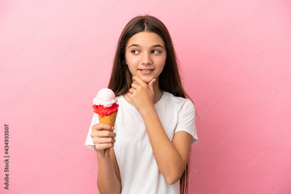 Little girl with a cornet ice cream over isolated pink background looking to the side and smiling Little girl with a cornet ice cream over isolated pink background looking to the side and smiling