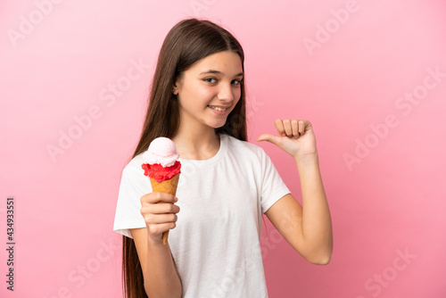Little girl with a cornet ice cream over isolated pink background proud and self-satisfied