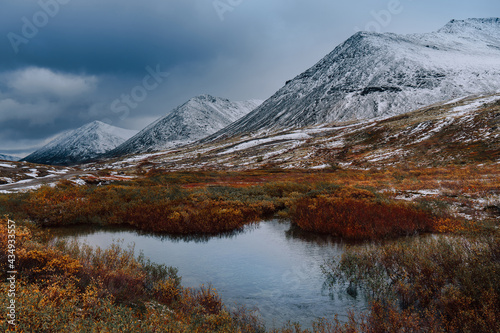 Autumn tundra and cold river on the background of misty snow-capped mountains, Arctic, Kola Peninsula