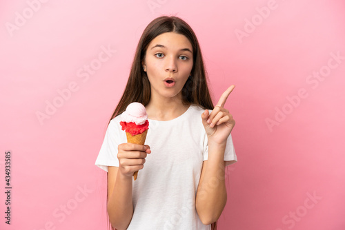Little girl with a cornet ice cream over isolated pink background intending to realizes the solution while lifting a finger up