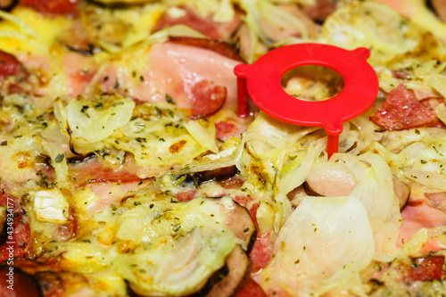 Close-up of sausages and onions on pizza with plastic stand.