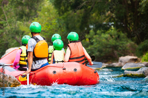 Group of family are rafting on the river turbulent flow. Extreme and enjoyment sport.