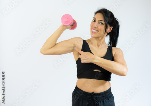 Attractive young fitness woman holding dumbbell isolated over white background.