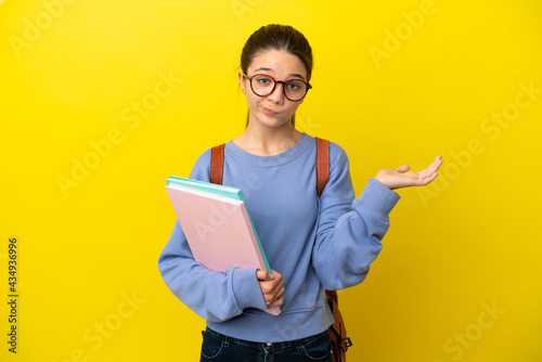 Student kid woman over isolated yellow background having doubts while raising hands