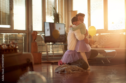 A young Dad and his little daughter are in a hug while have a ballet training at home together. Family, together, home
