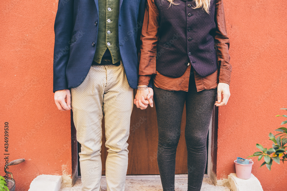 Middle section couple in love holding hands standing front door Middle section couple in love holding hands standing front door