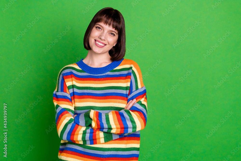 Fototapeta premium Photo of pretty adorable young woman wear striped sweater smiling arms crossed empty space isolated green color background