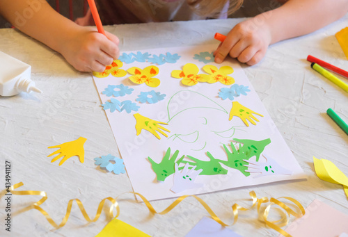 Child making homemade greeting card. little girl making card for mom with flowers from paper as gift for Mothers day, Birthday or Valentines day . Arts crafts concept.