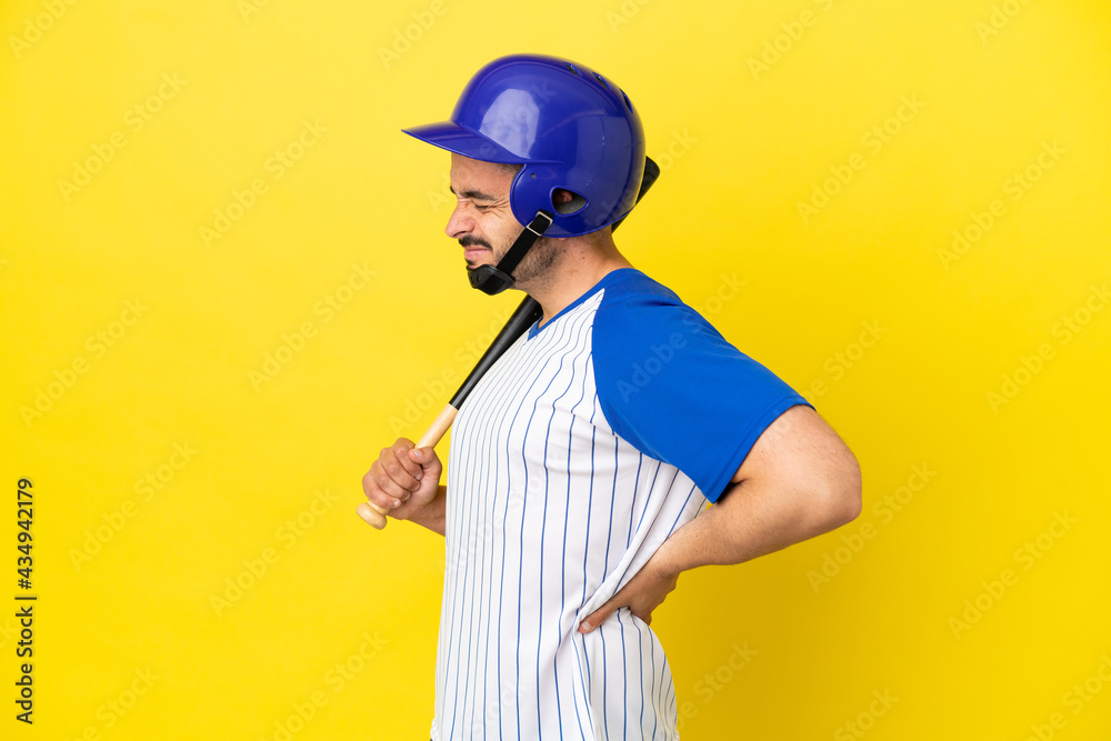 Young caucasian man playing baseball isolated on yellow background suffering from backache for having made an effort