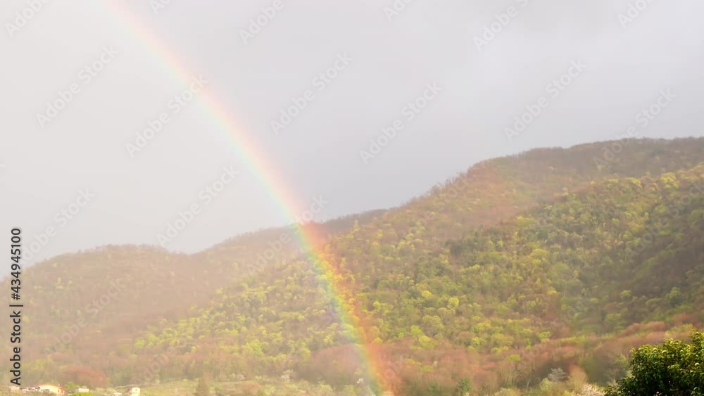 Amazing rainbow appearing on background of sky and mountains in sunlight, natural phenomenon appeared after raining while sun shining. Multicolored spectrum, abstract imagination, formation of Amazing rainbow appearing on background of sky and mountains in sunlight, natural phenomenon appeared after raining while sun shining. Multicolored spectrum, abstract imagination, formation of