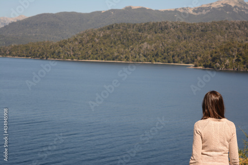 woman with her back turned on the shores of a pensive lake with mountains © Lautaro