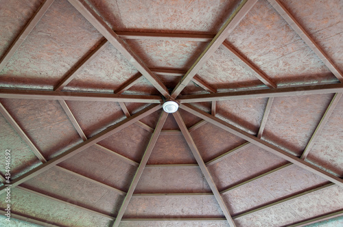 Wooden roof street arbor view from inside. Pergola roof from the inside. Wooden roof with radial beams. Inside of wooden gazebo