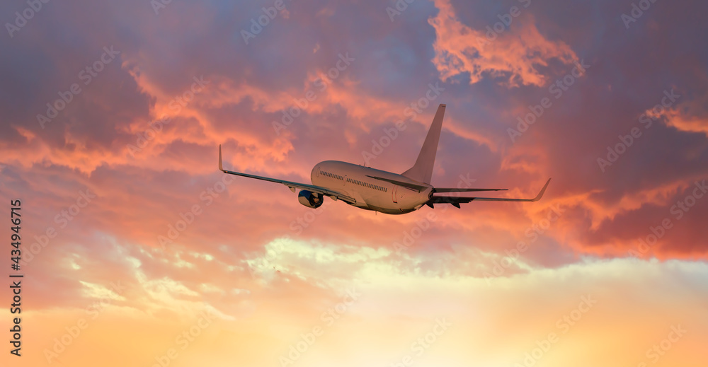 Airplane flying above tropical sea at amazing sunset