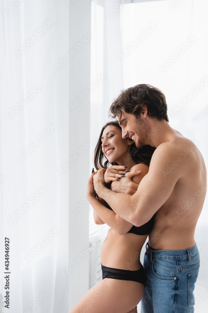 Smiling man in jeans hugging sensual girlfriend with closed eyes Smiling man in jeans hugging sensual girlfriend with closed eyes