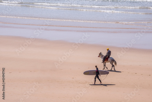 Paisaje con surfista y jinete en la costa de Taghazout en el sur de Marruecos
