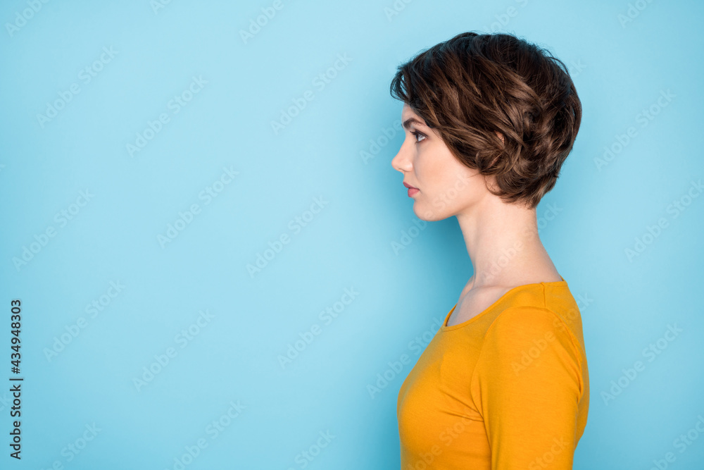 Profile portrait of nice serious brunette lady look empty space wear yellow shirt isolated in vivid blue color background Profile portrait of nice serious brunette lady look empty space wear yellow shirt isolated in vivid blue color background