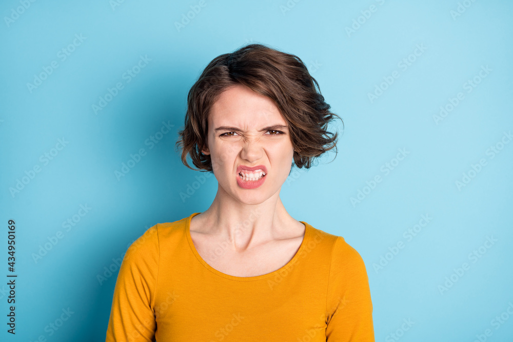 Photo of angry brunette lady show teeth wear yellow shirt isolated in vivid blue color background Photo of angry brunette lady show teeth wear yellow shirt isolated in vivid blue color background