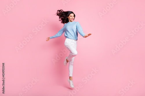 Full length photo of funny lady jump look empty space wear blue sweater isolated pink color background